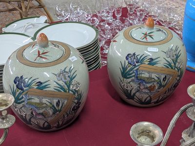 deux vases posés sur une table où se trouvent des assiettes et des tasses