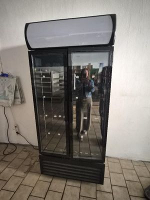 someone taking a picture of their reflection in the glass door of a refrigerator