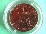 a coin in a clear plastic container on a green surface