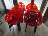 trois chaises rouges placées les unes à côté des autres sur un plancher en bois