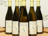 six bouteilles de vin sont alignées sur un tonneau en bois