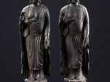 deux statues de bouddhas assis sur une surface noire