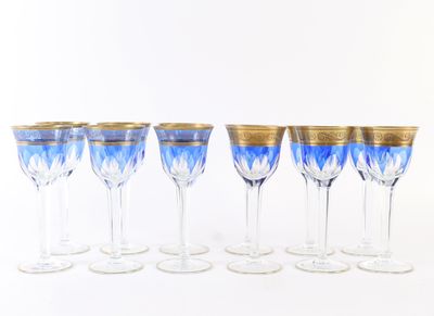 six verres à vin bleus et dorés alignés sur une surface blanche