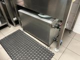 a stainless steel sink in a kitchen with a black mat on the floor
