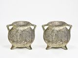 paire de vases en argent munis d'anses, posés sur des socles, sur fond blanc