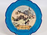 une assiette bleue sur laquelle est représenté un village