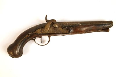un vieux pistolet avec une poignée en bois sur une surface blanche