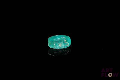 a close up of a green emerald stone on a black surface