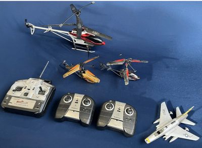 four remote controls and a remote control helicopter on a blue surface