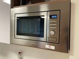 a stainless steel microwave with a digital clock on it