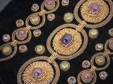 une photo en gros plan d'un sac à main noir orné d'or et de pierres précieuses