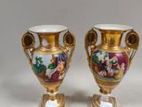 une paire de vases en or ornés de scènes peintes, posés sur une table