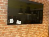a television mounted on a brick wall above a row of chairs