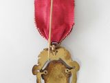 an old medal with a red ribbon hanging from it ' s side