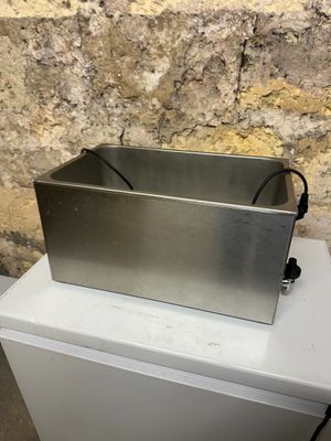 une photo représentant une boîte en acier inoxydable posée sur une table blanche