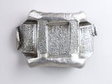 silver buckle with writing on it on a white surface