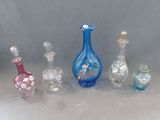 cinq bouteilles en verre de couleurs différentes posées les unes à côté des autres