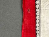 a close up of a red and white scarf on a gray surface