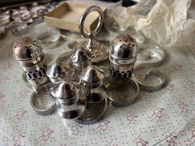 une salière et une poivrière en argent posées sur une assiette en verre
