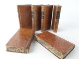 four old books are lined up in a row on a white surface