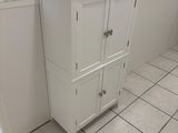 a white cabinet in a bathroom with a mirror above it