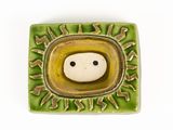 a small ceramic object with a smiley face in the center