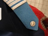 a man wearing a uniform with a blue tie and a badge on his lapel