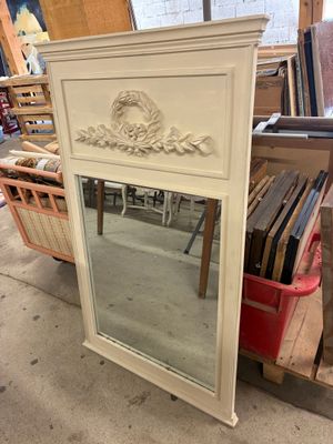 a mirror that is sitting on the floor in front of a shelf