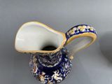 a blue and white pitcher with a gold decoration on it