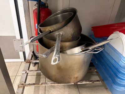 several pots and pans are stacked on a shelf in a kitchen