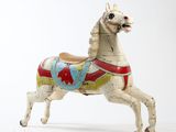a toy horse that is standing on a white surface
