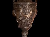 a silver vase that is sitting on a black surface