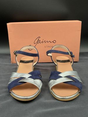 une paire de sandales bleues et argentées, avec une boîte en arrière-plan