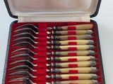 six forks in a case on a white table