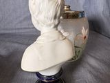 a white bust of a man on a blue vase
