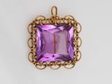 a close up of a purple glass pendant on a white surface