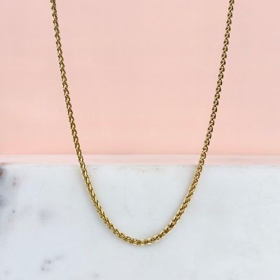 un collier à chaîne en or sur fond rose