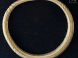 a close up of a gold necklace on a black surface
