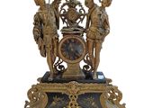 une horloge en or surmontée de statues