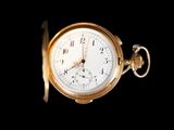 gros plan d'une montre de poche en or sur fond noir