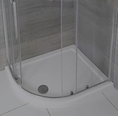 une douche avec une porte vitrée, située dans un coin de la pièce
