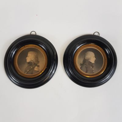 deux portraits encadrés représentant deux hommes, dans des cadres noirs, accrochés à un mur blanc