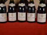 six bottles of wine are lined up on a red table cloth