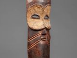 a carved wooden figure of a man with a mask on his head