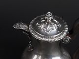 a silver tea pot with a wooden handle on a table