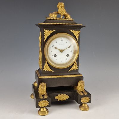 une horloge noire et dorée surmontée d'un lion