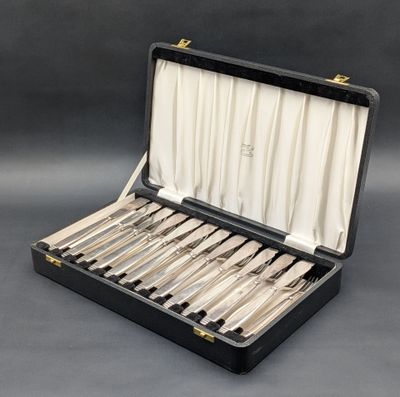 un coffret noir contenant de l'argenterie, posé sur une surface grise