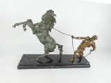 statue of a man pulling a horse with a rope on a marble base