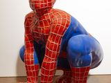 une statue représentant Spider-Man assis sur un plancher en bois