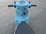 un scooter bleu avec un siège noir dans la rue